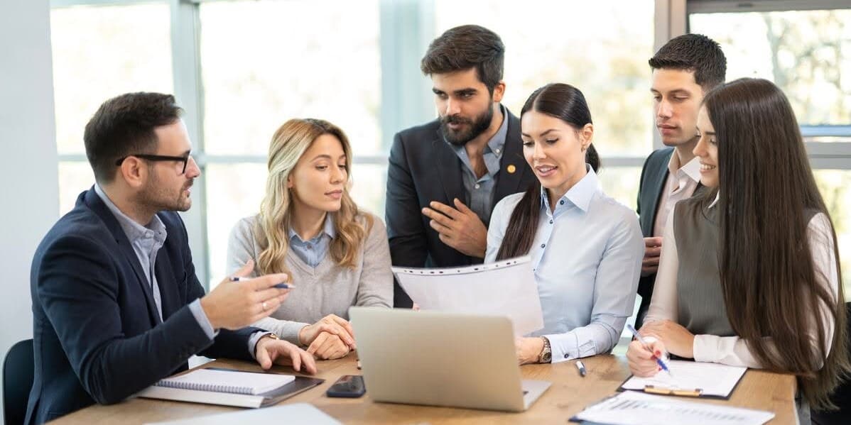 Equipo de profesionales revisando un documento junto a una notebook en una sala de reuniones